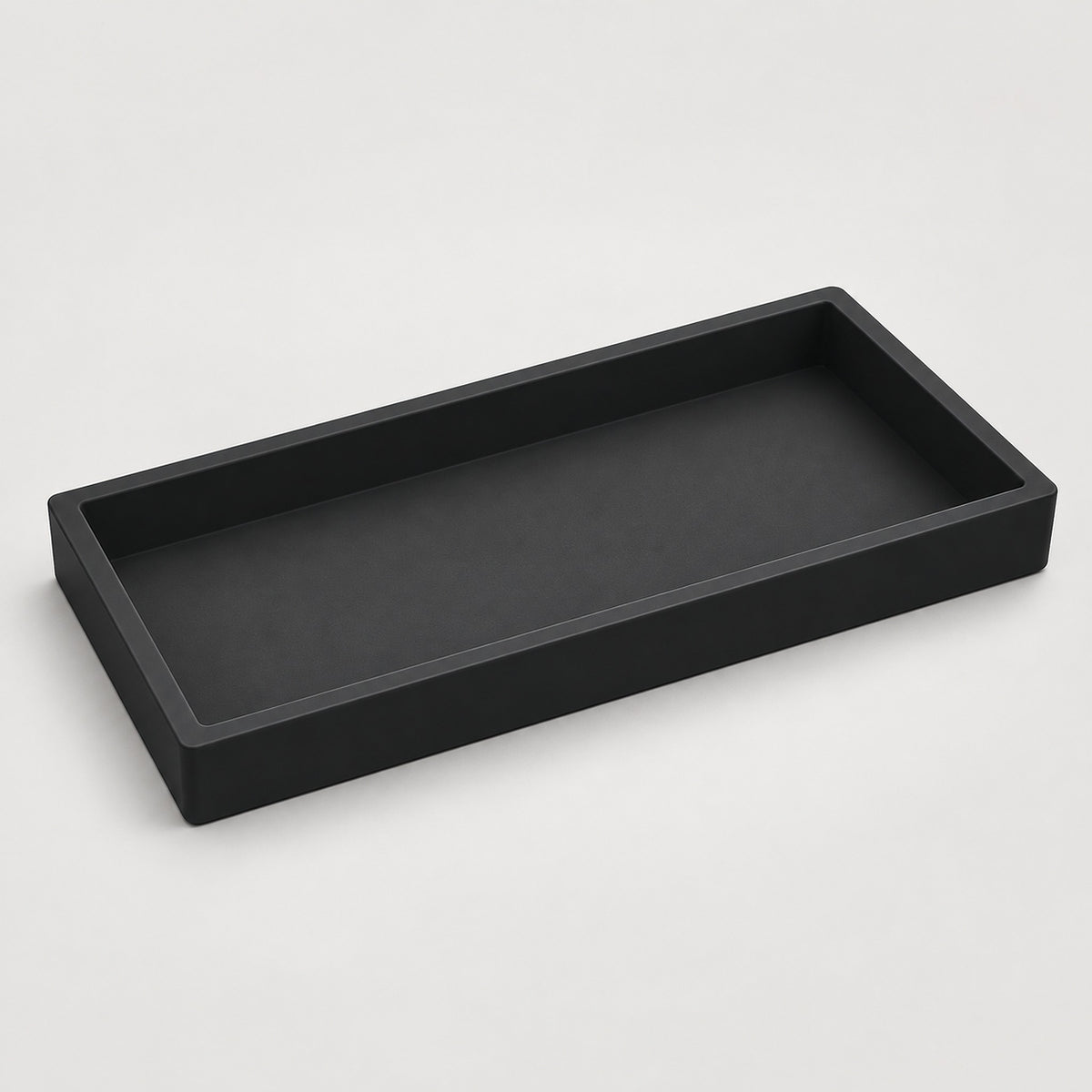 A minimalist black rectangular tray with a low raised rim, shown from an elevated perspective on a light gray background.