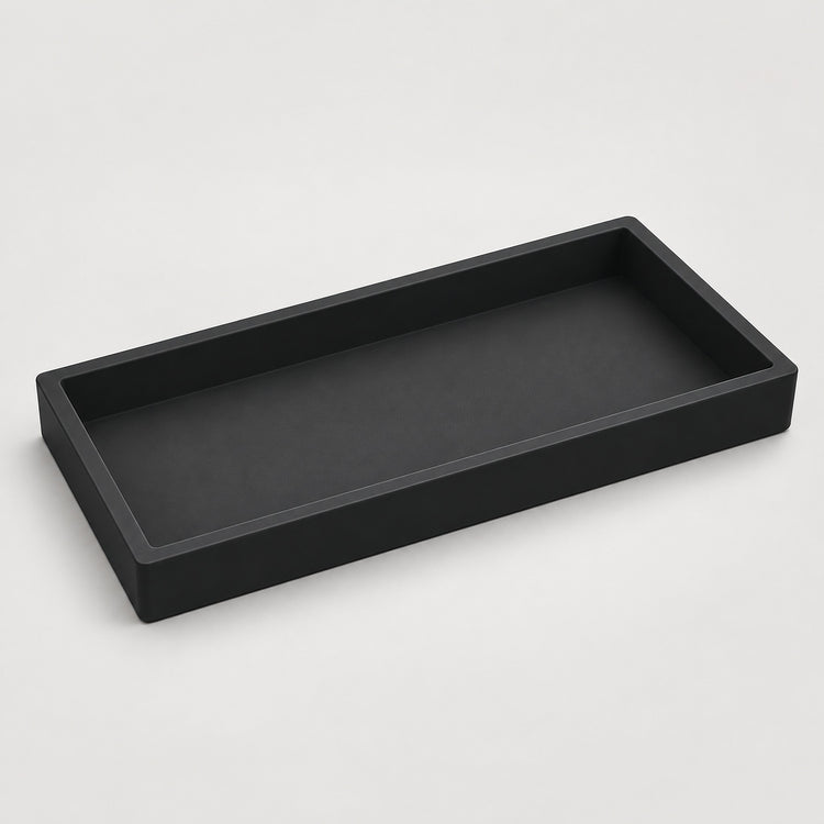 A minimalist black rectangular tray with a low raised rim, shown from an elevated perspective on a light gray background.