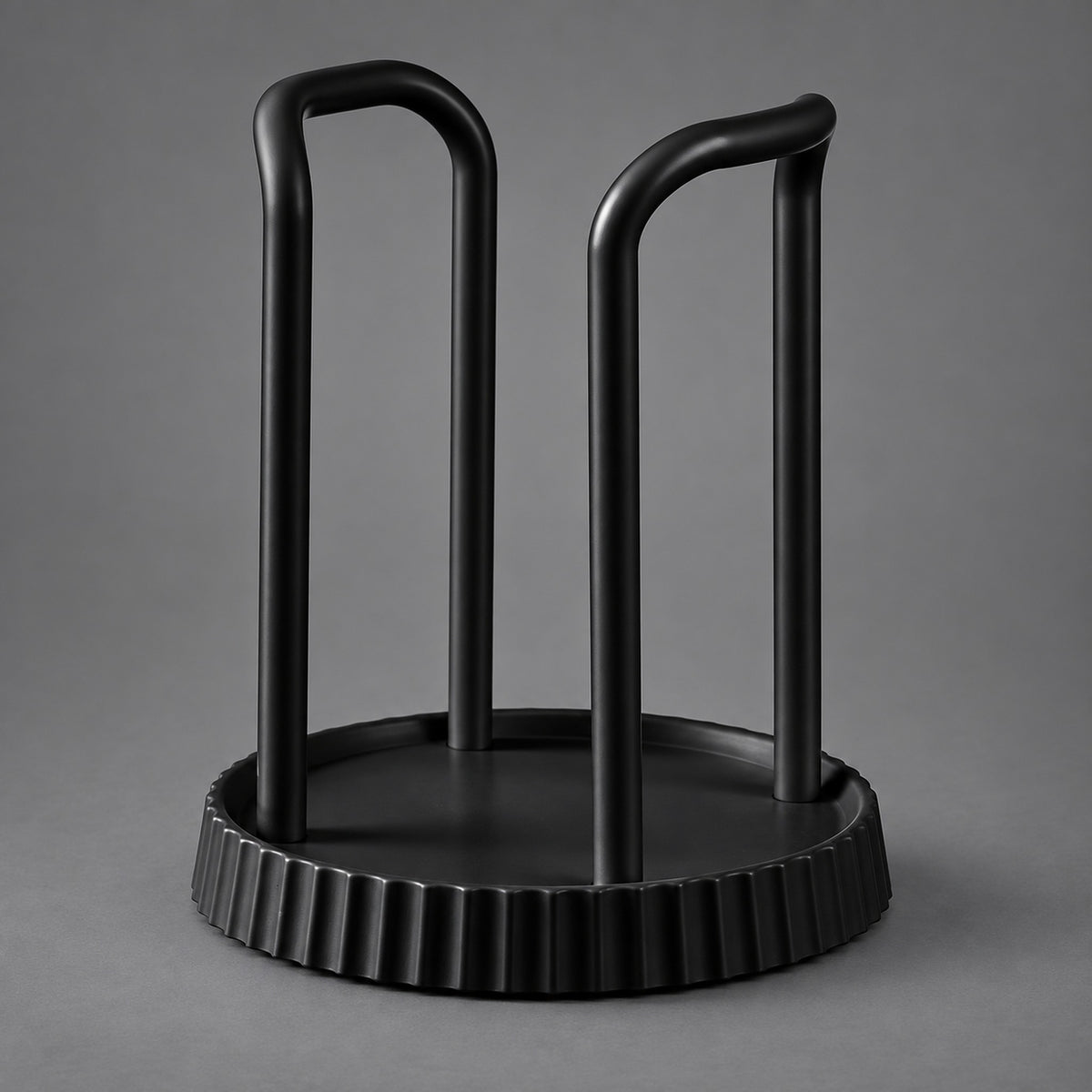 A matte black metal wine bottle rack with a circular base and two upright curved arms, shown on a neutral gray background.