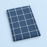 Single blue grid cotton towel, folded studio view.