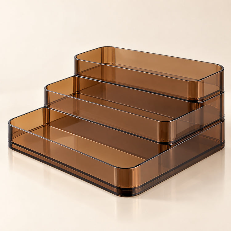 Three-tier translucent amber brown plastic organizer trays on a light beige background.