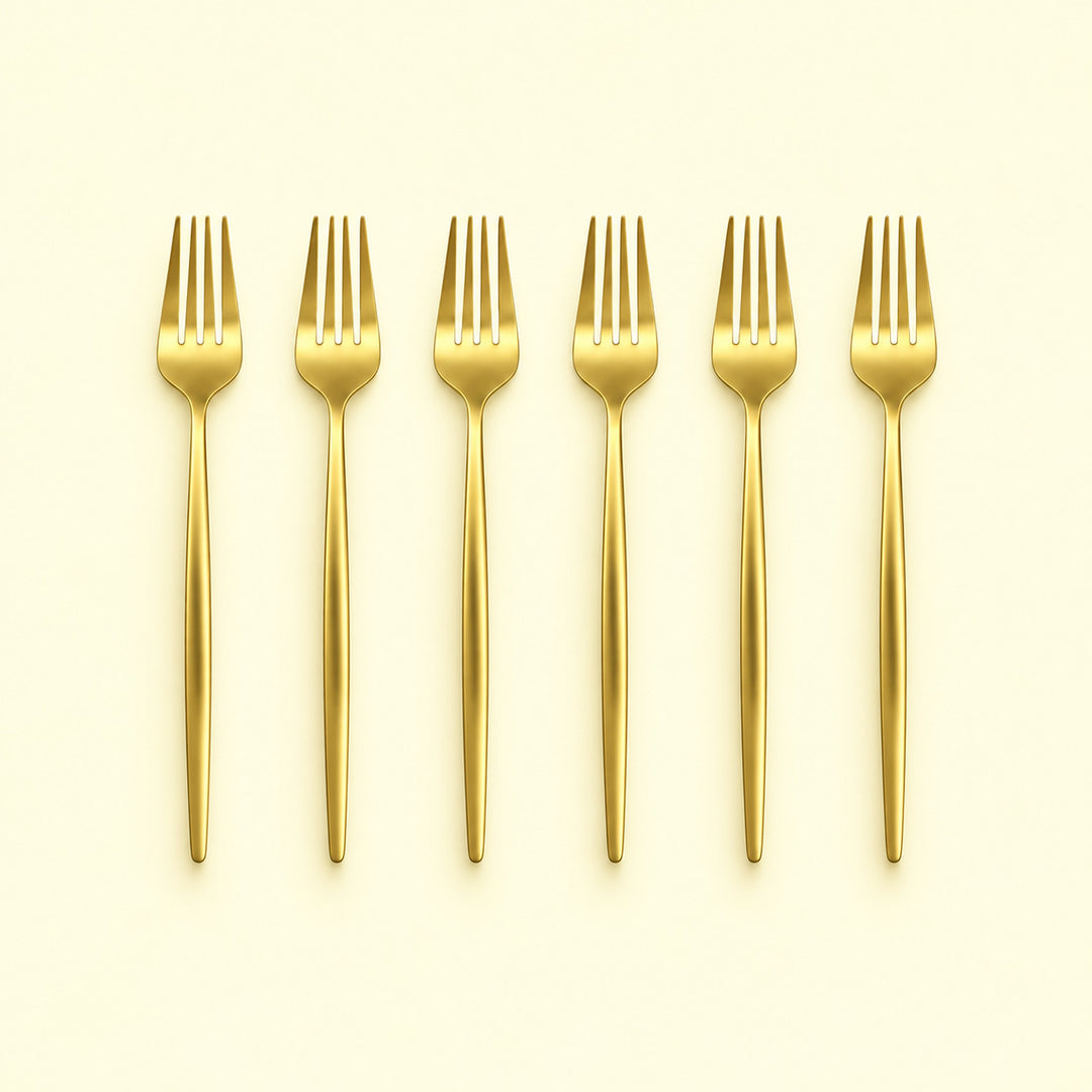 Set of six gold dinner forks on a pale yellow studio background.
