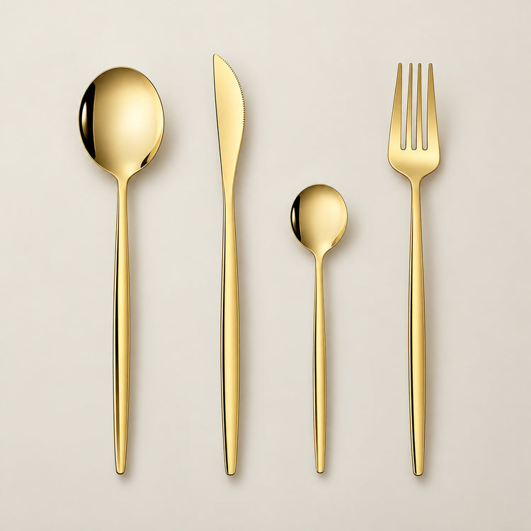 Gold four-piece flatware set on a pale gold-tinted studio background.
