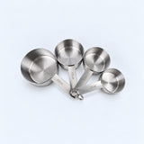 Four silver measuring cups on a pale gray studio background.
