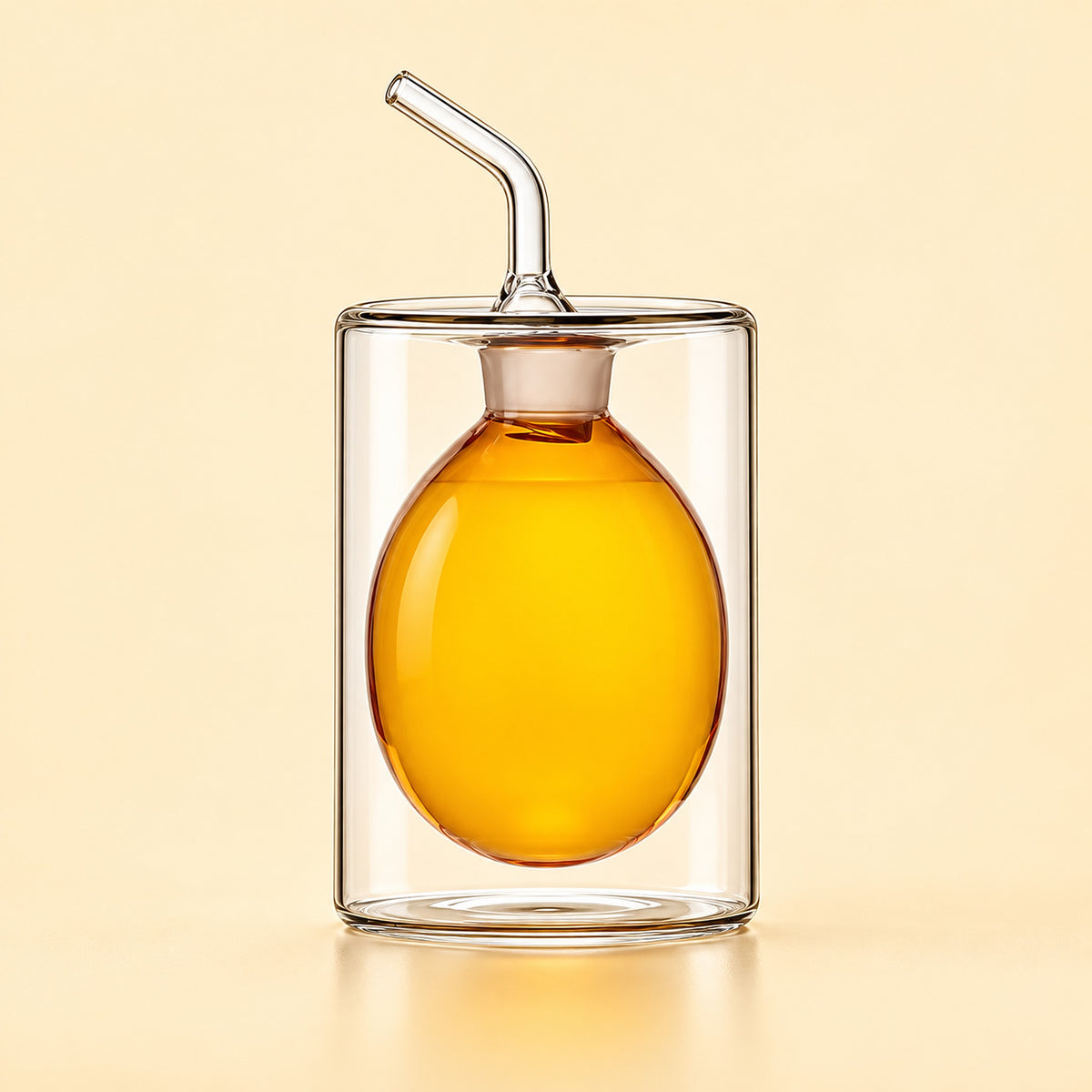 A clear glass double-walled cup with a matching glass lid and angled glass straw, featuring a large oval glass insert filled with amber-colored liquid, set against a solid pale beige background.