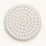 A round, off-white felted wool coaster with a textured, bumpy petal-like pattern, photographed from directly above on a clean white background.