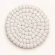 A round, off-white felted wool coaster with a textured, bumpy petal-like pattern, photographed from directly above on a clean white background.