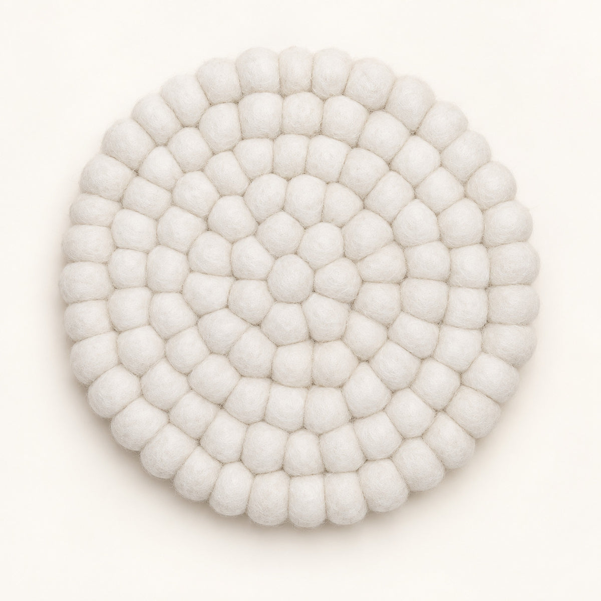 A round, off-white felted wool coaster with a textured, bumpy petal-like pattern, photographed from directly above on a clean white background.