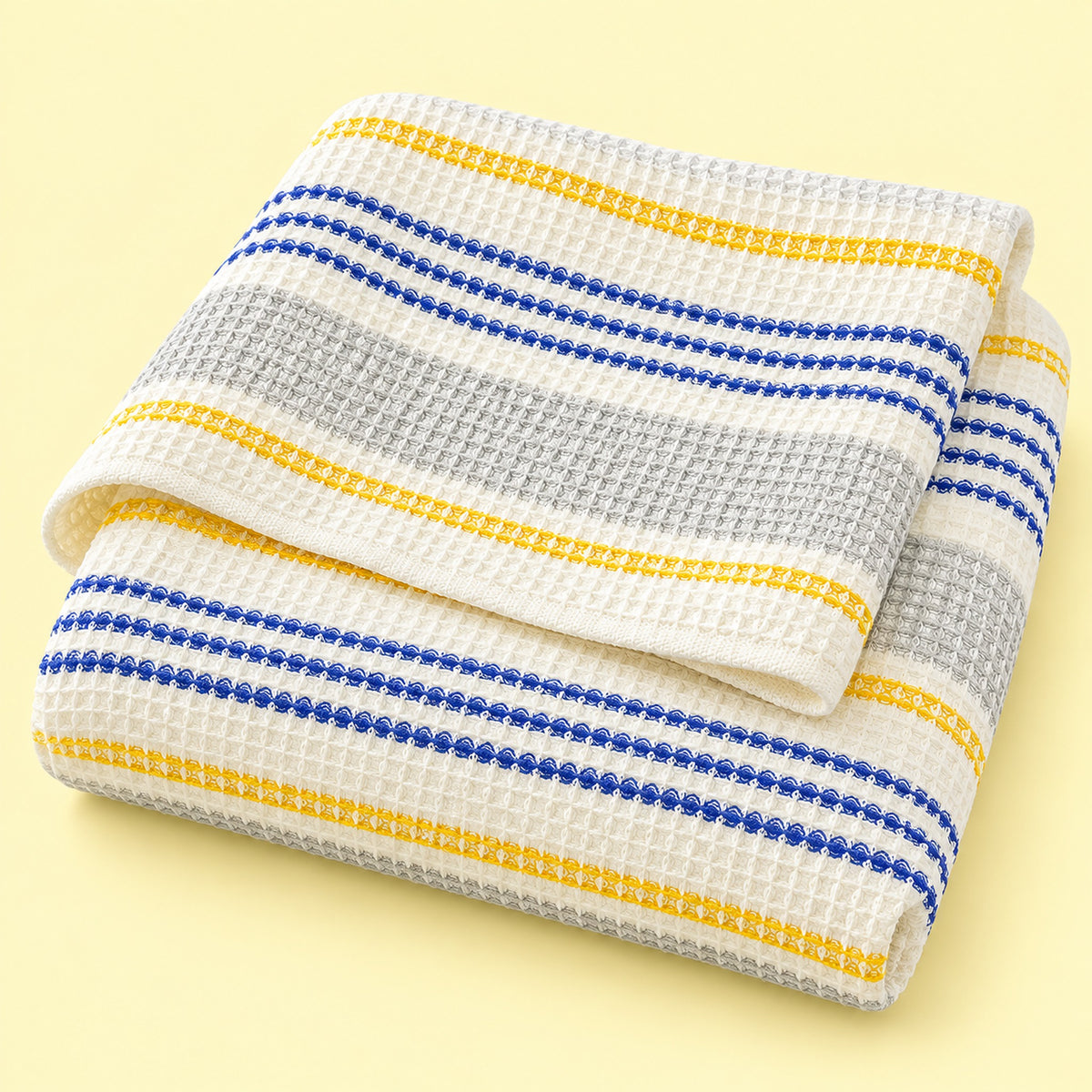 Yellow striped waffle cotton towel on pale yellow studio background; size selected separately.