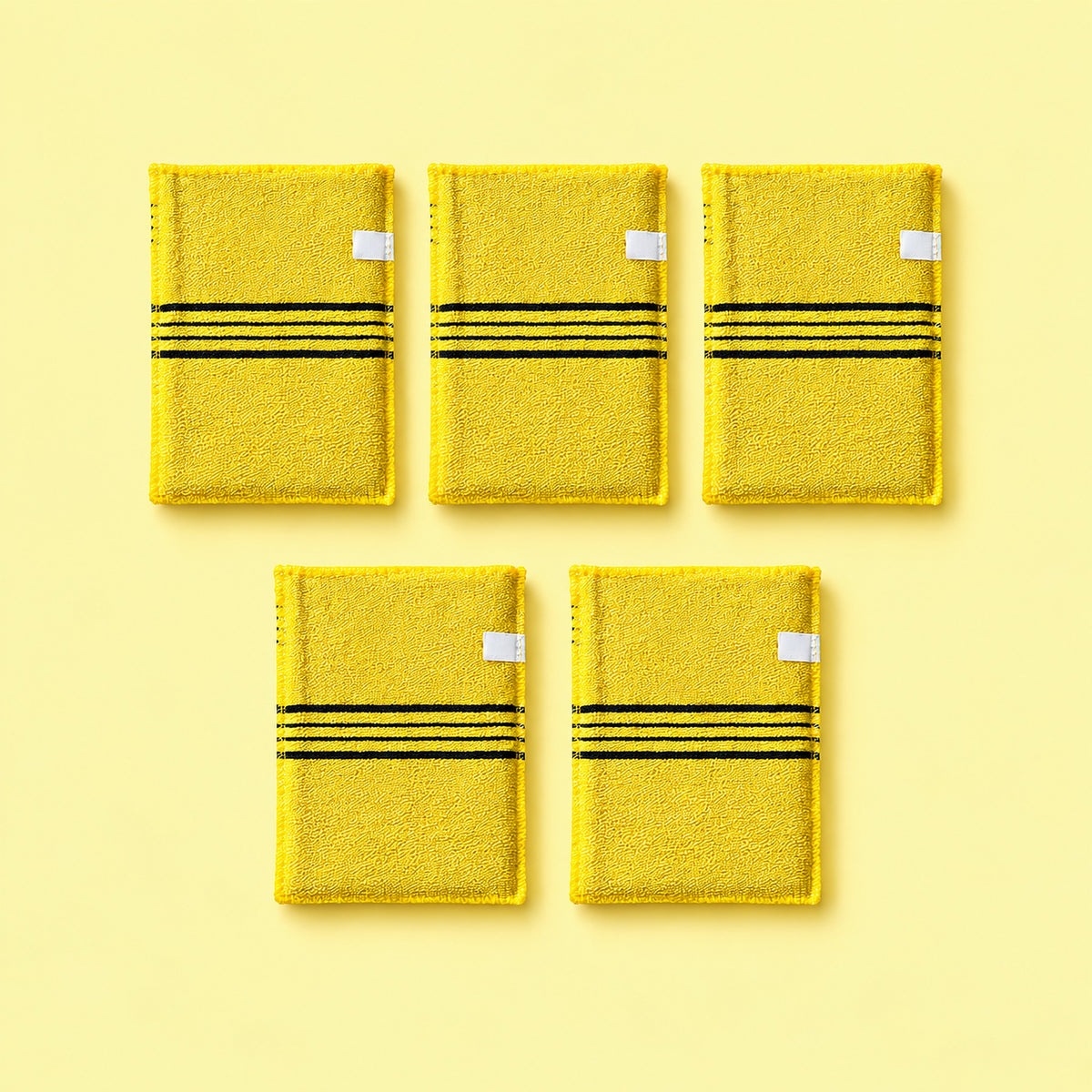 Yellow variant: five yellow exfoliating mitts with white side tabs on a pale yellow background.