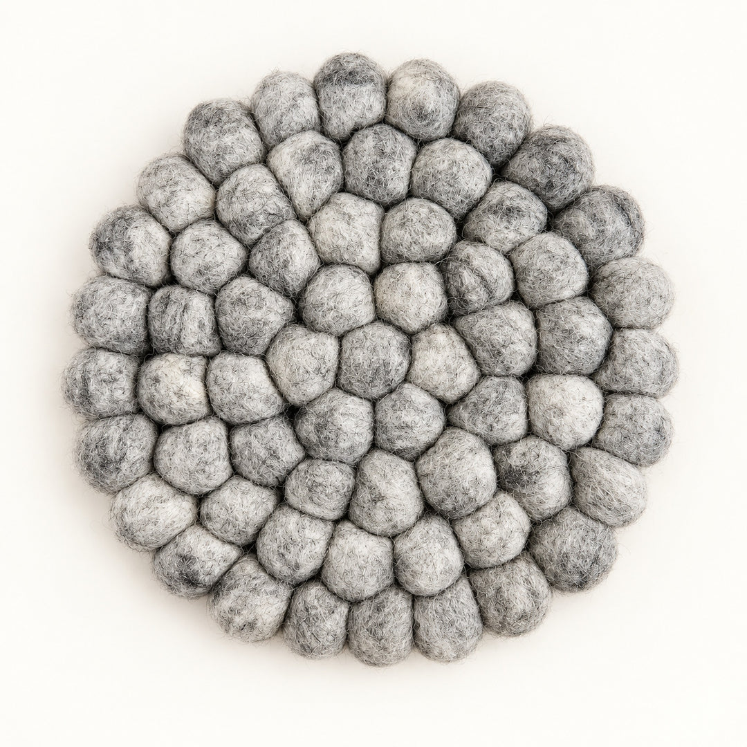 A round felt mat made of small gray pom-poms, photographed from directly above on a plain white background.