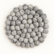 A round felt mat made of small gray pom-poms, photographed from directly above on a plain white background.