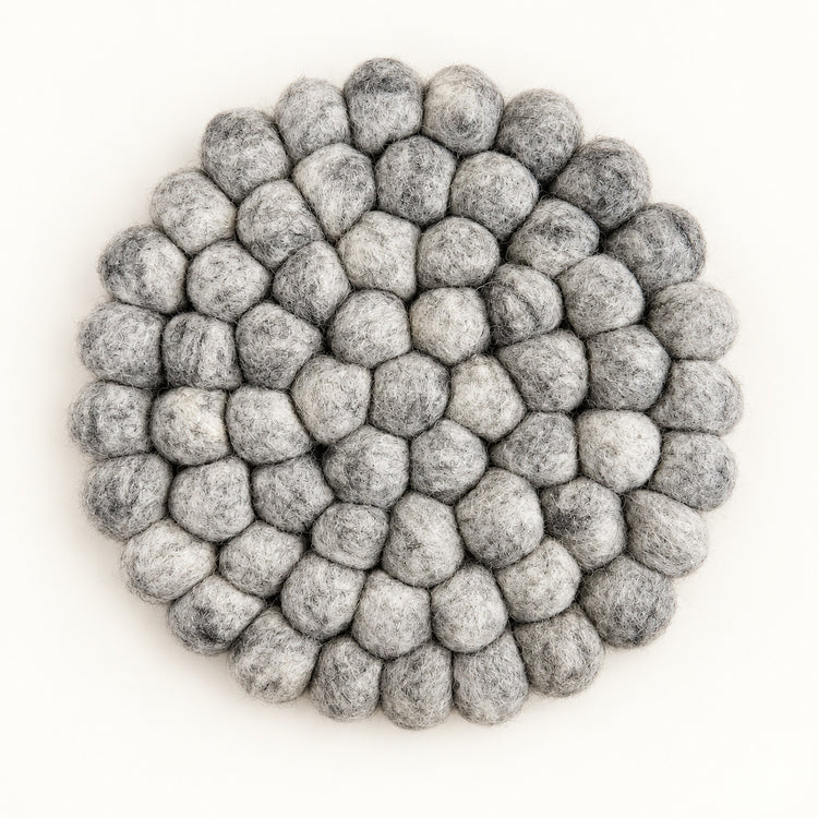 A round felt mat made of small gray pom-poms, photographed from directly above on a plain white background.