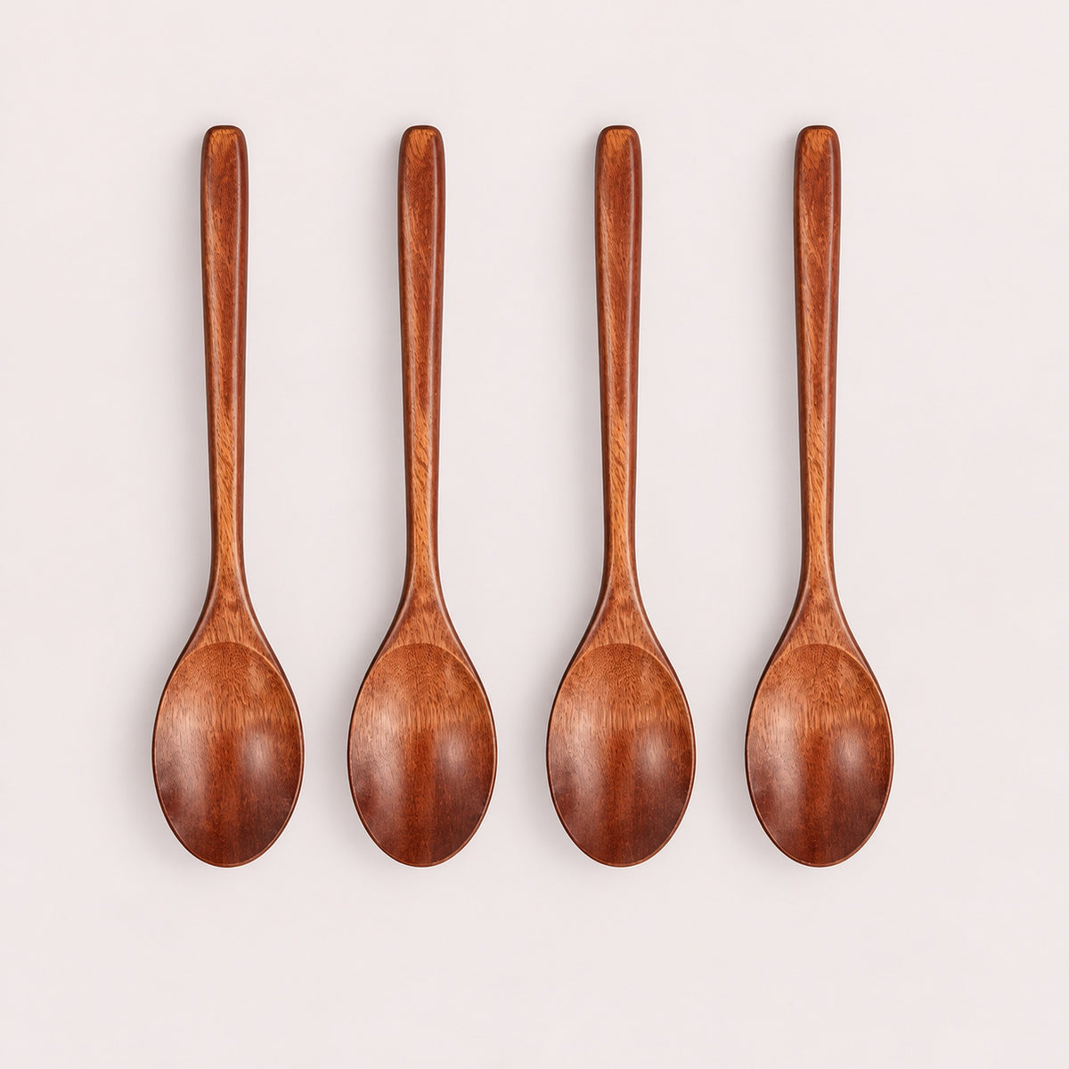 Four Brown wood spoons on a pale blush-gray studio background.