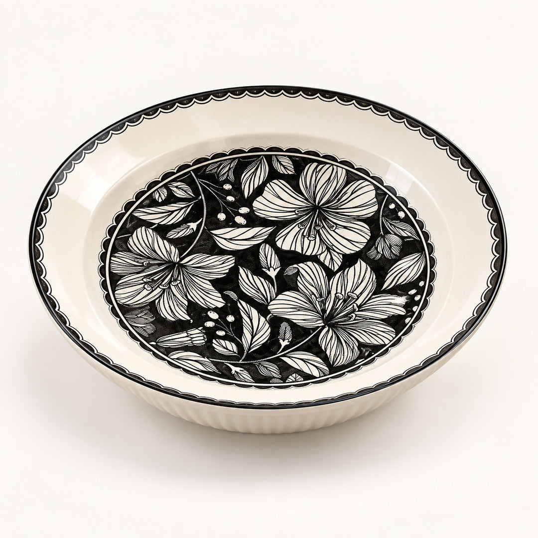 An oval ceramic bowl with a black and white floral pattern on the inner surface and a black scalloped rim, shown on a clean white background.
