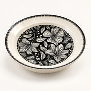 An oval ceramic bowl with a black and white floral pattern on the inner surface and a black scalloped rim, shown on a clean white background.