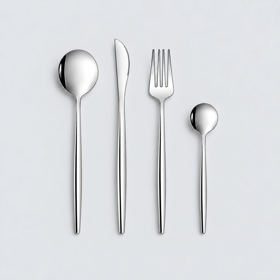 Silver four-piece flatware set on a pale gray studio background.