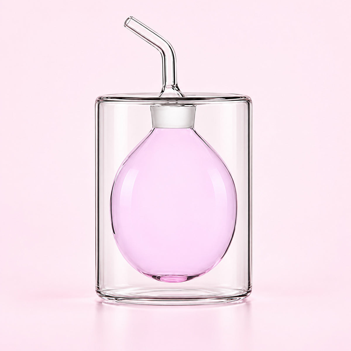 A clear glass double-walled tumbler with a matching clear glass pour spout lid and angled straw, filled with light pink liquid, set against a solid pale pink background.