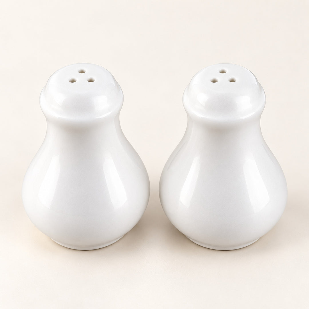 A pair of glossy white ceramic salt and pepper shakers with three-hole tops, set against a plain off-white background.