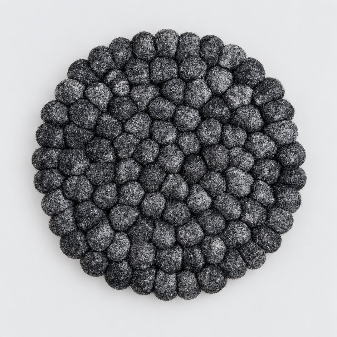 A round black and gray textured felt rug made of raised, bumpy petal-like loops, photographed from directly above on a light gray background.