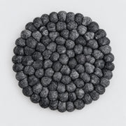 A round black and gray textured felt rug made of raised, bumpy petal-like loops, photographed from directly above on a light gray background.