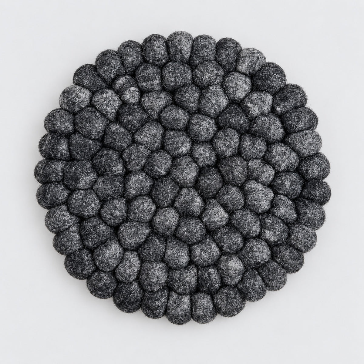 A round black and gray textured felt rug made of raised, bumpy petal-like loops, photographed from directly above on a light gray background.