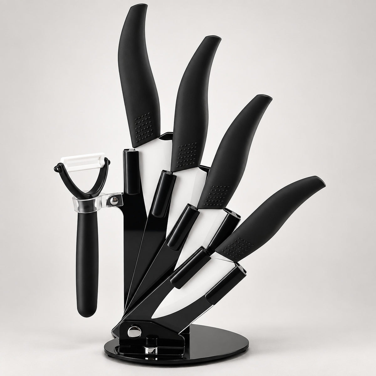 A black kitchen knife set with matching black-handled tools, including knives and a peeler, displayed on a round stand against a light gray background.
