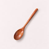 One Brown wood spoon on a pale blush-gray studio background.