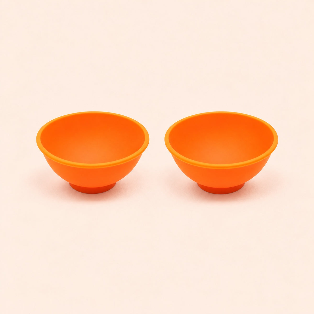 Two orange silicone mini bowls, open tops and pedestal bases.