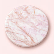 A round marble coaster with a white and light pink base and delicate rose gold veining, shown from a top-down view on a solid pale pink background.