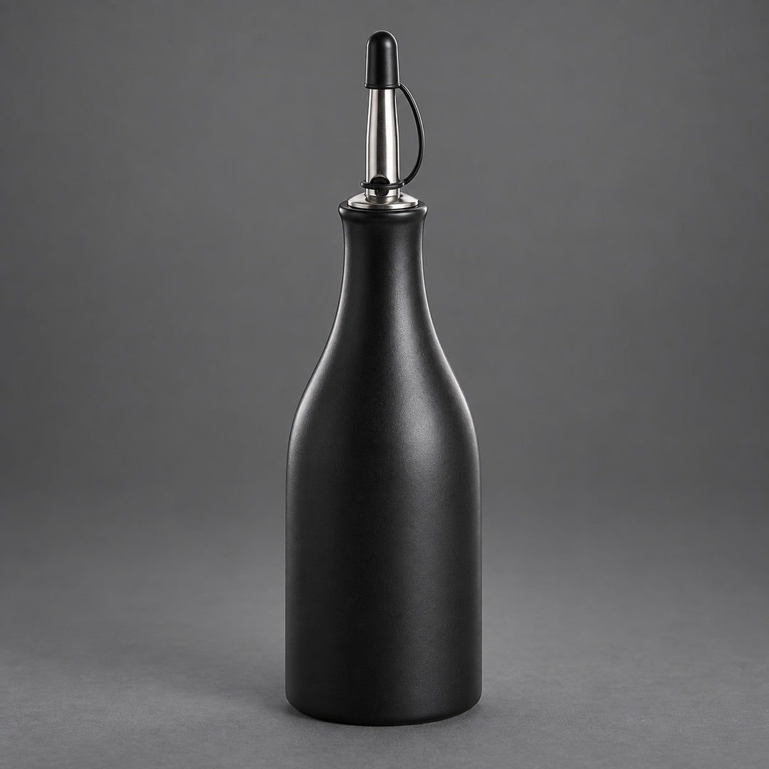 A matte black bottle with a metallic silver and black pour spout, set against a solid gray studio background.