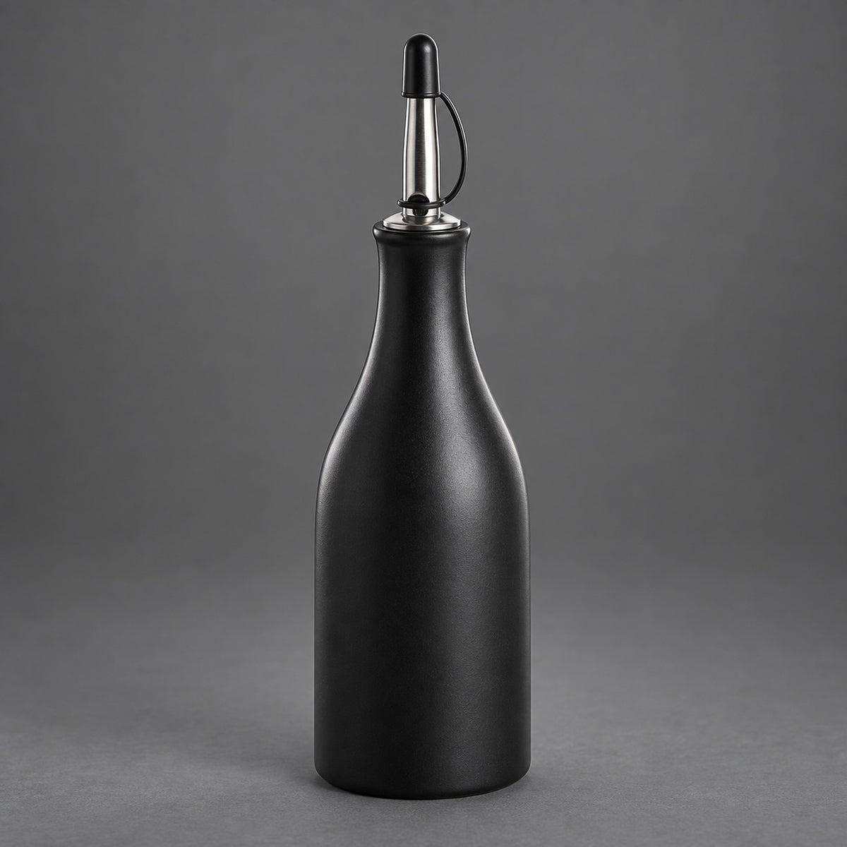 A matte black bottle with a metallic silver and black pour spout, set against a solid gray studio background.