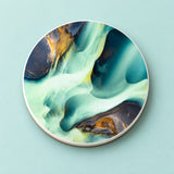 One teal and gold abstract swirls printed ceramic coaster on a light studio background.