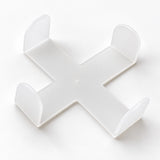 One empty white cross-shaped coaster holder, coasters sold separately.