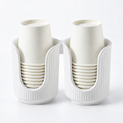 A white plastic dual-cup holder with two vertical compartments, each holding a stack of off-white paper cups, shown on a clean white background.
