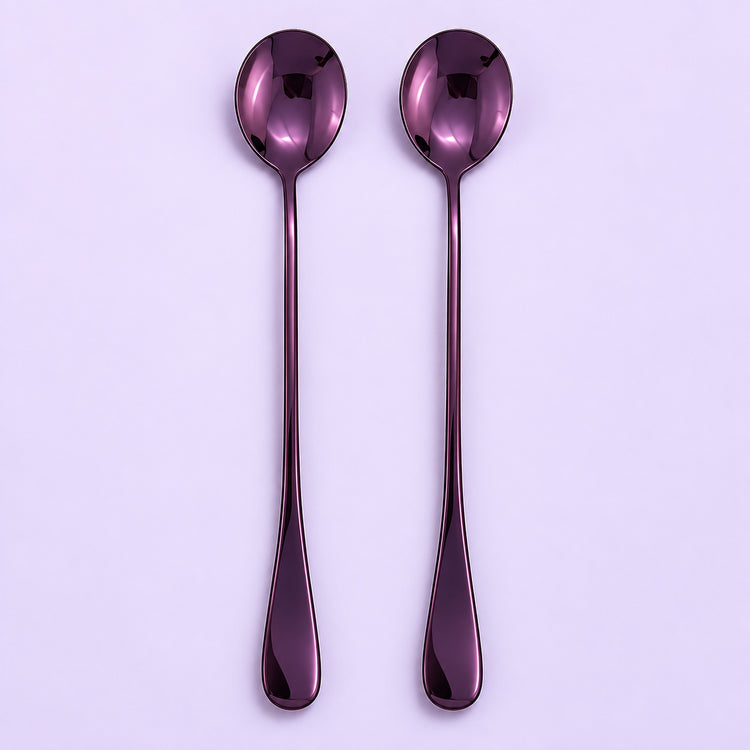 Two long-handled spoons with a glossy metallic purple finish, arranged vertically side-by-side on a light lavender background.