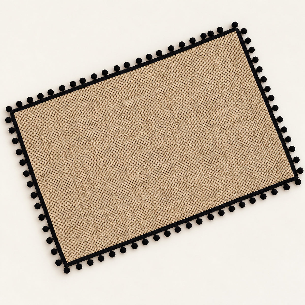 One tan placemat with black pom pom trim, 30 x 45 cm.