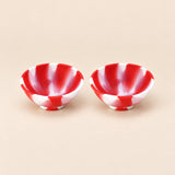 Two red and white swirl silicone mini bowls, open tops and pedestal bases.