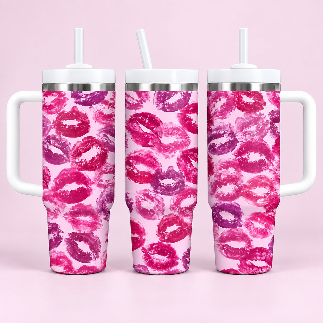 Three handled stainless steel tumblers with white straws, featuring a repeating pink and purple lip print pattern on a light pink background, set against a solid light pink backdrop.