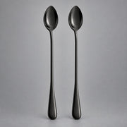 Two long-handled spoons with a glossy black finish, standing upright side-by-side against a neutral gray background.