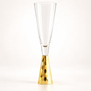 A clear champagne flute with a hammered gold metallic base, photographed against a seamless white background.