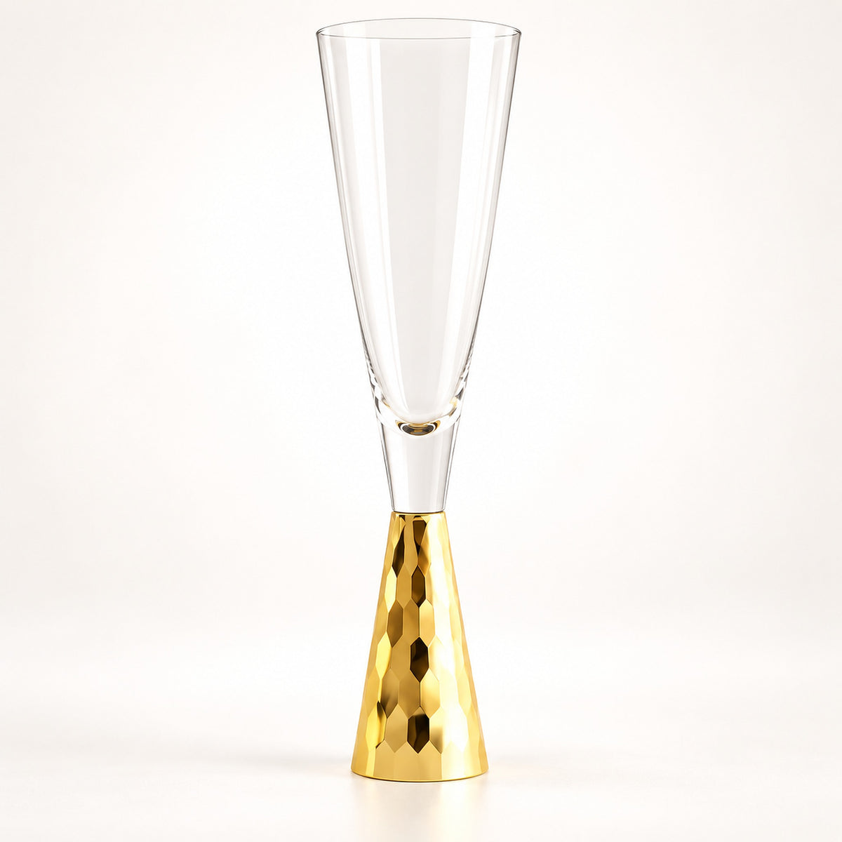 A clear champagne flute with a hammered gold metallic base, photographed against a seamless white background.