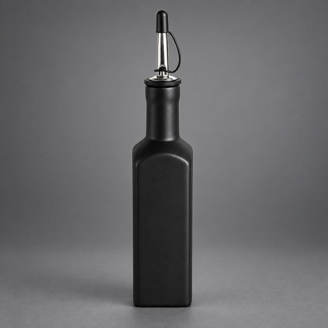 A matte black rectangular bottle with a pour spout, shown centered against a neutral gray studio background.