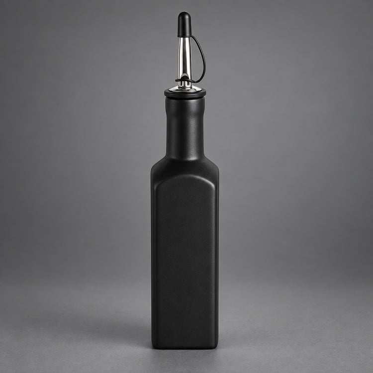 A matte black rectangular bottle with a pour spout, shown centered against a neutral gray studio background.