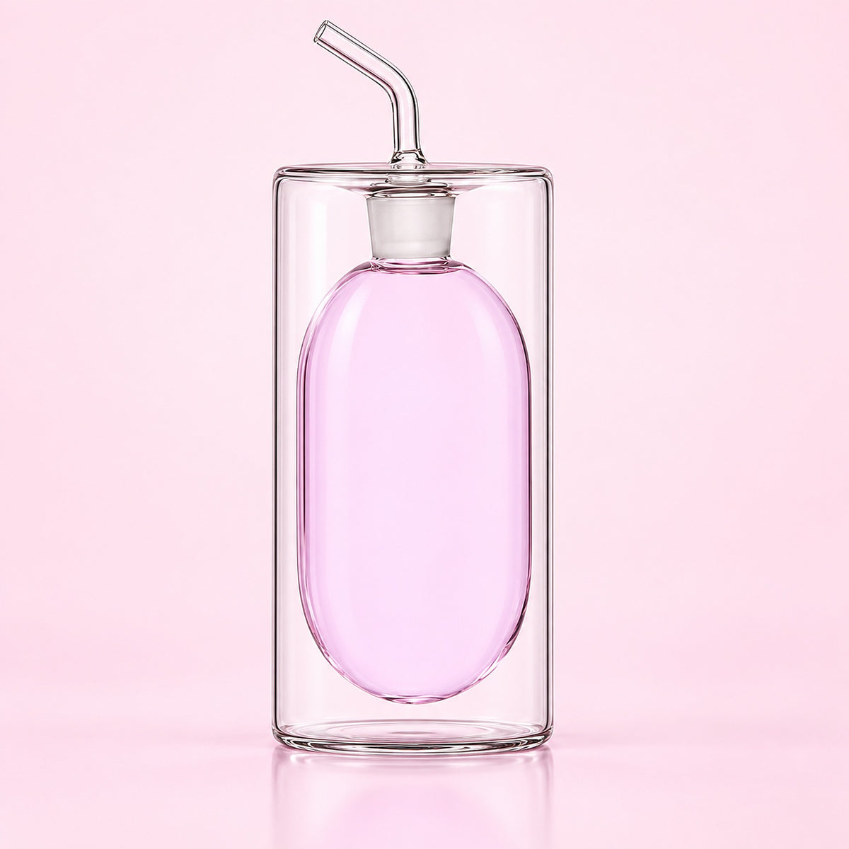 A clear glass double-walled bottle with an oval-shaped pink interior and a curved glass straw, set against a solid light pink background.