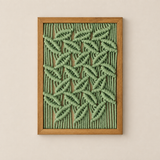 A framed abstract wall art piece featuring textured, raised green woven or knotted lines in a geometric leaf-like pattern, set in a light natural wood frame against a warm beige wall.
