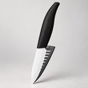 A kitchen knife with a matte black handle and a silver blade featuring a black serrated edge, shown against a neutral light gray background.