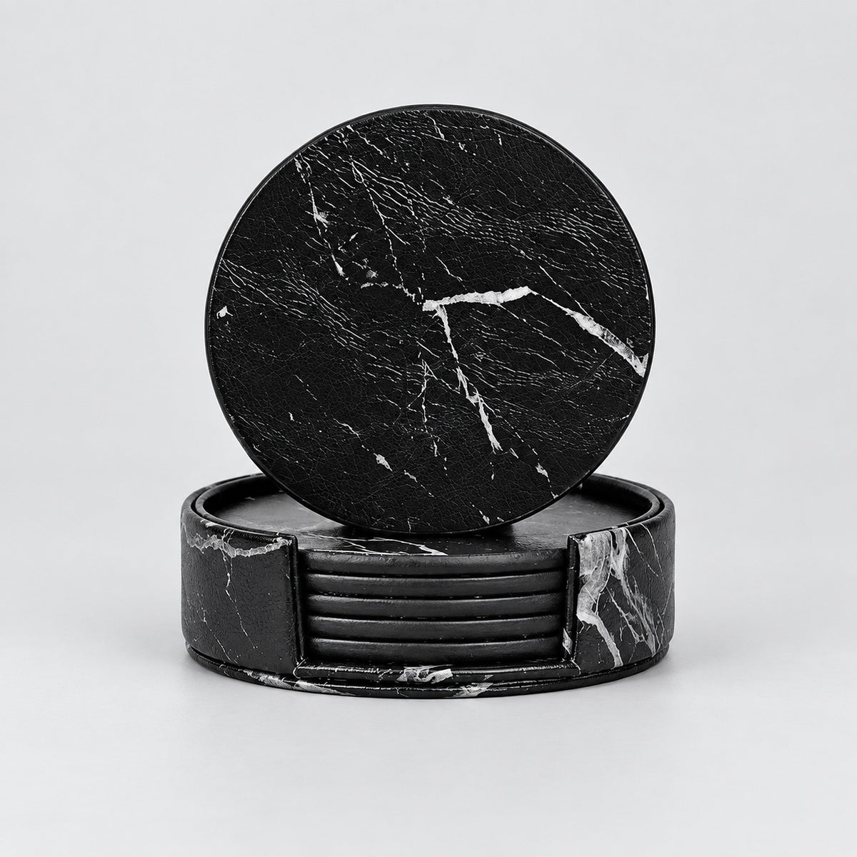 A set of black marble coasters, with one round coaster leaning against a stack of rectangular coasters on a light gray background.