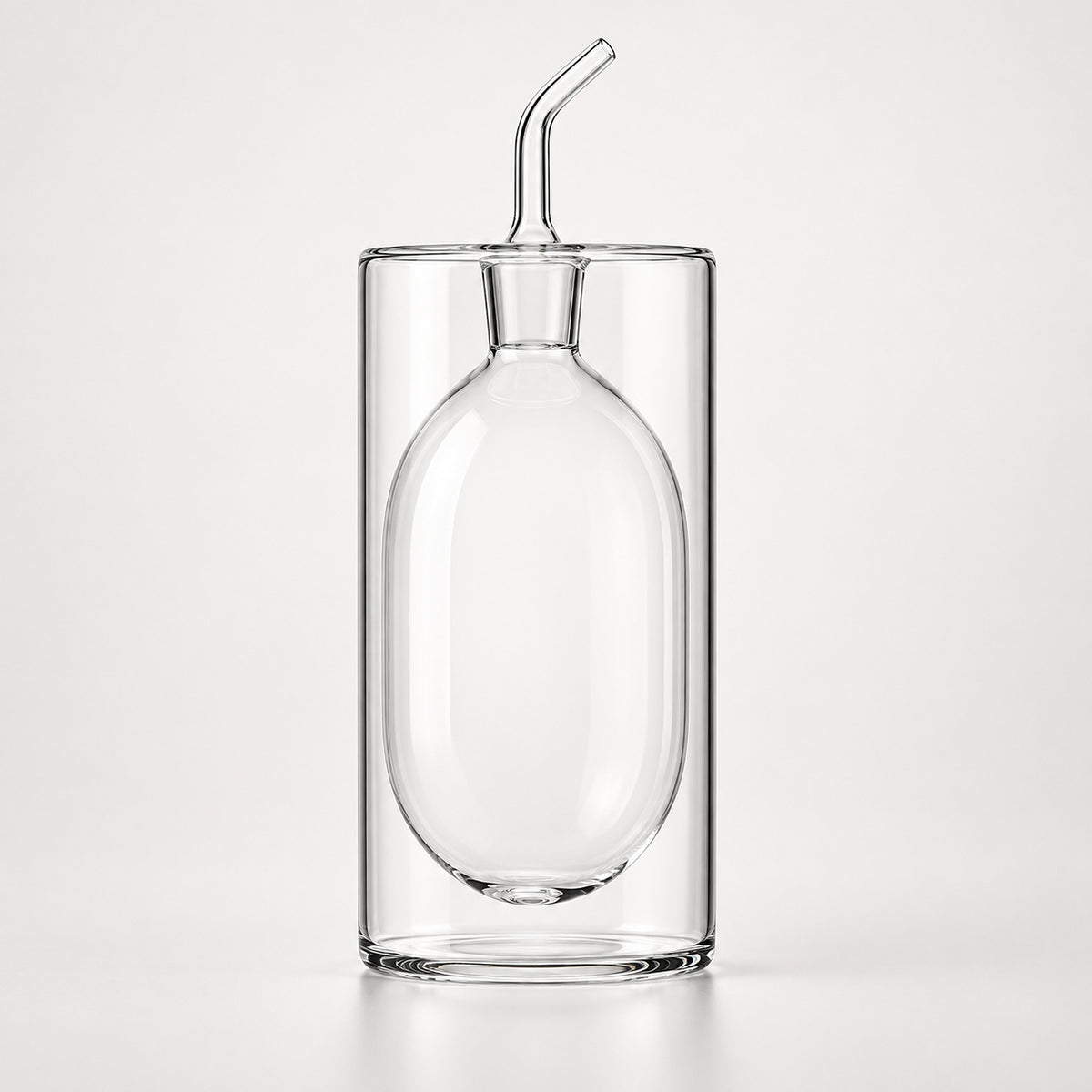 Clear glass double-walled tumbler with an integrated oval-shaped glass insert and a small angled glass pour spout on top, shown on a light gray studio background.