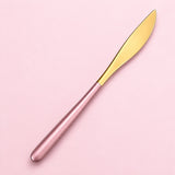 One pink and gold dinner knife on a soft studio background.